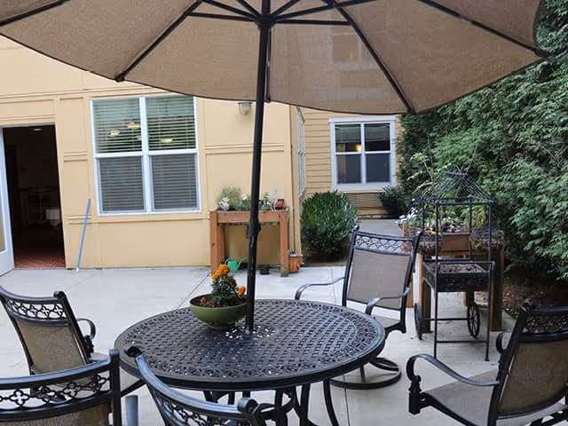 Outdoor courtyard patio with a round metal table, umbrella, and chairs.