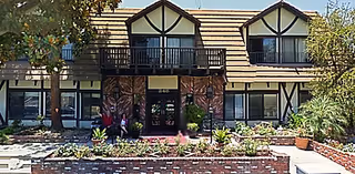 Exterior view of Jasmin Terrace at El Molino showing a Tudor-style building with a landscaped front garden and a small group near the entrance.