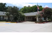 Front view of College Street Health Care Center with entrance, flagpole, and surrounding trees.