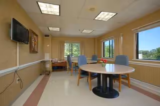 A round table with blue chairs sits in a beige dining room.