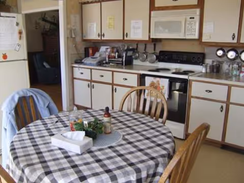 A small kitchen and round table with checkered tablecloth in a homey dining area.
