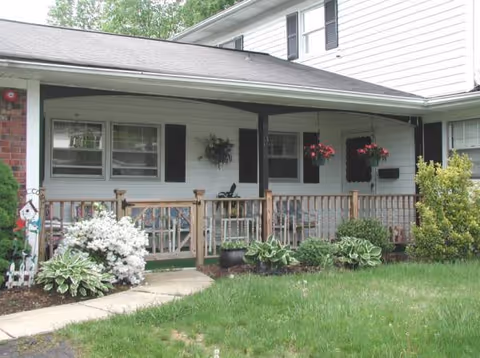 Exterior of Rene's House Assisted Living with a front porch, plants, and hanging baskets.
