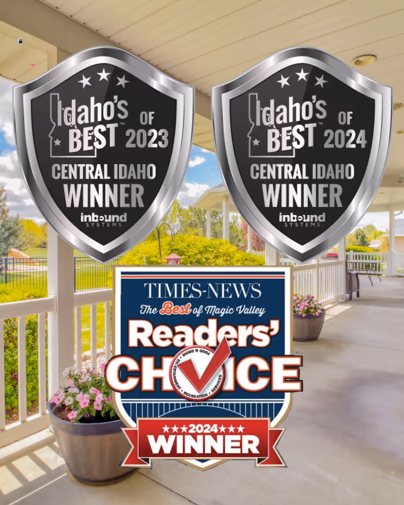Covered outdoor patio area with white railings and columns, potted flowers, and a view of green trees and bushes under a partly cloudy sky.