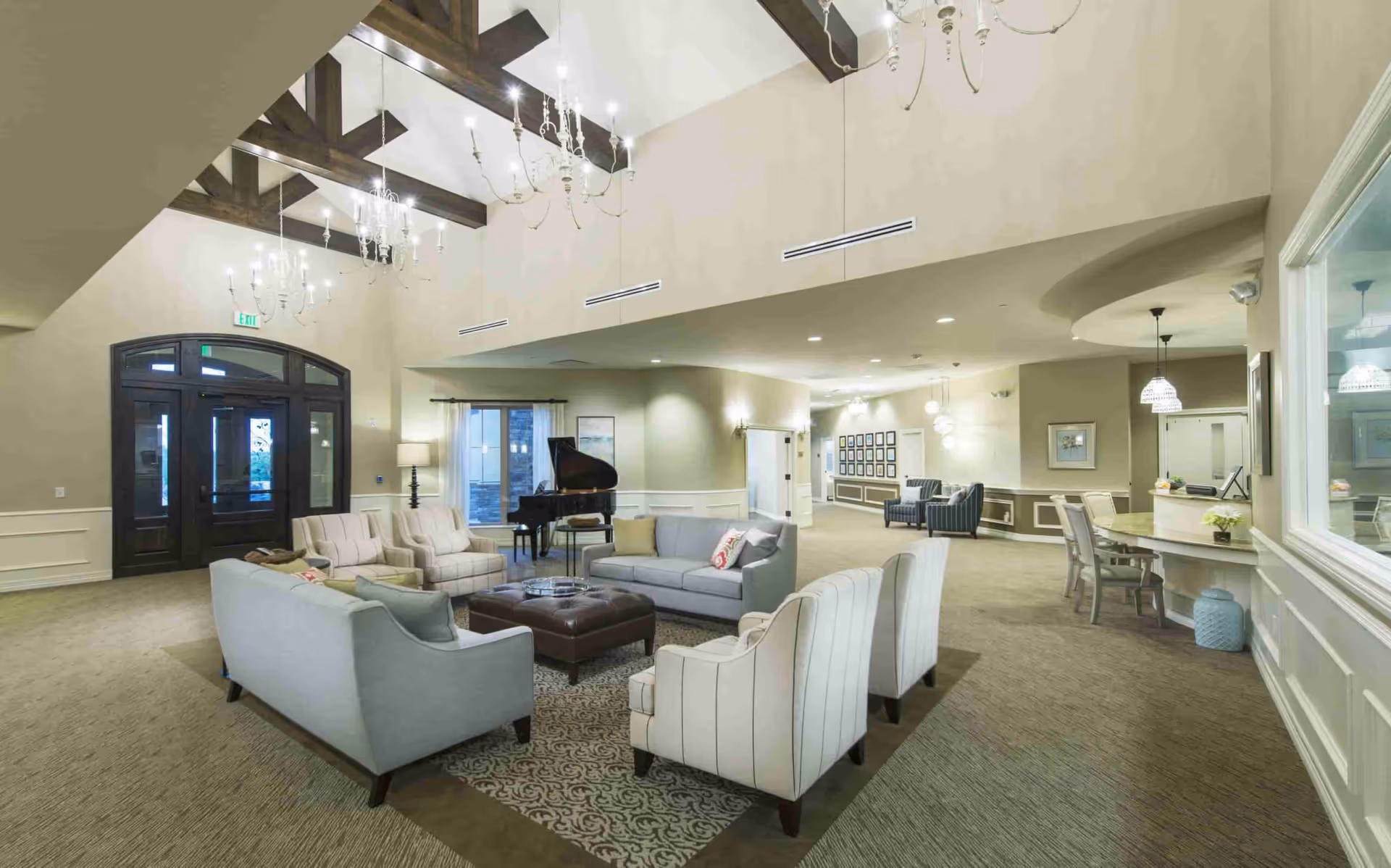 Spacious senior living common lounge with sofas, armchairs, chandeliers and a grand piano.