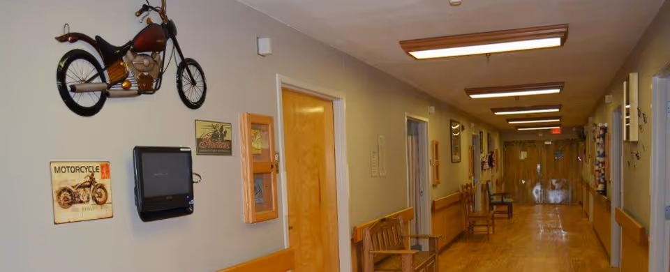 Long, well-lit interior hallway with wooden benches, doors and motorcycle-themed wall decor.