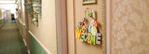 Narrow hallway in a luxury senior living facility with a Welcome sign on a door.