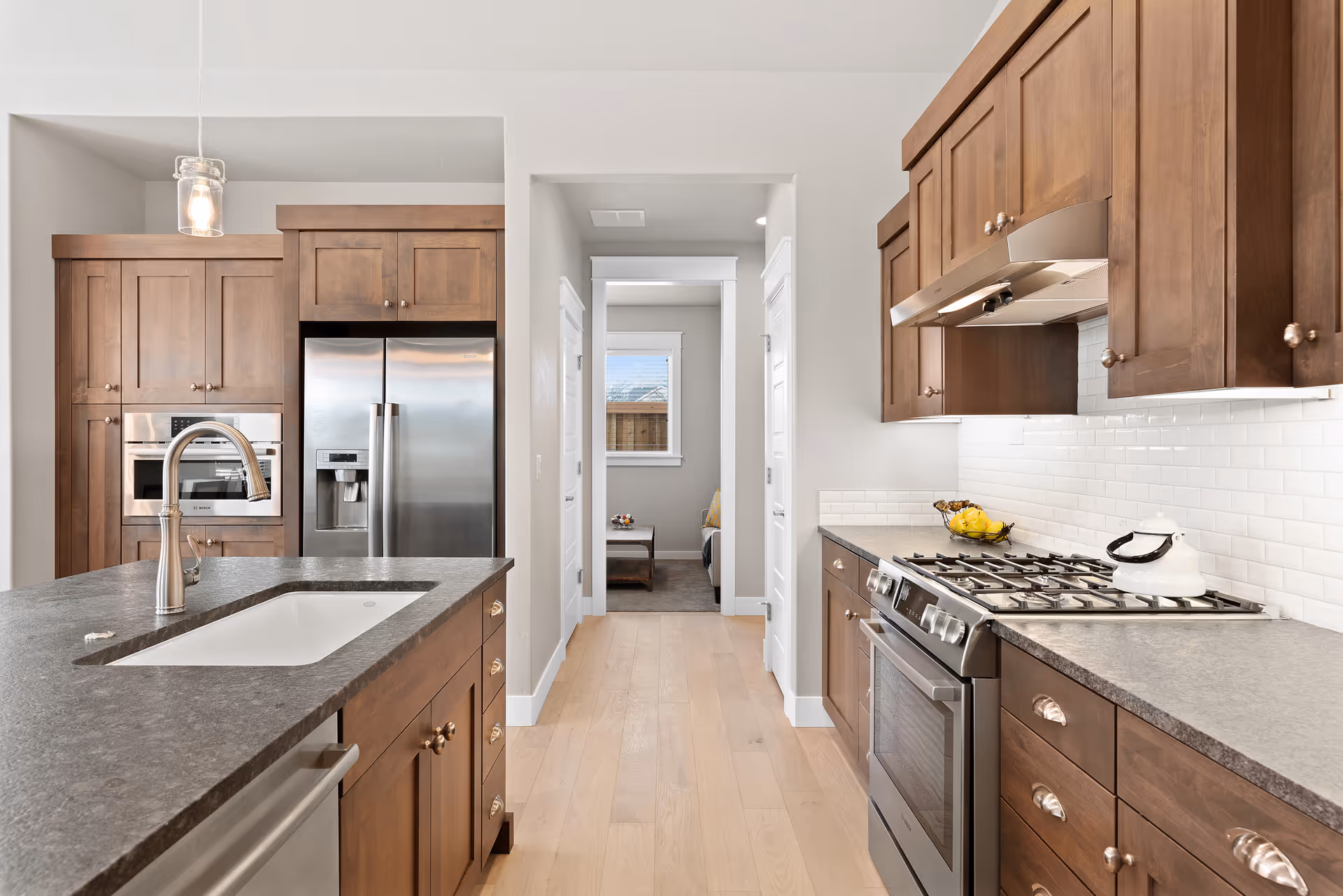 Bright modern kitchen with wooden cabinets, a center island with sink, stainless steel refrigerator and gas stove.