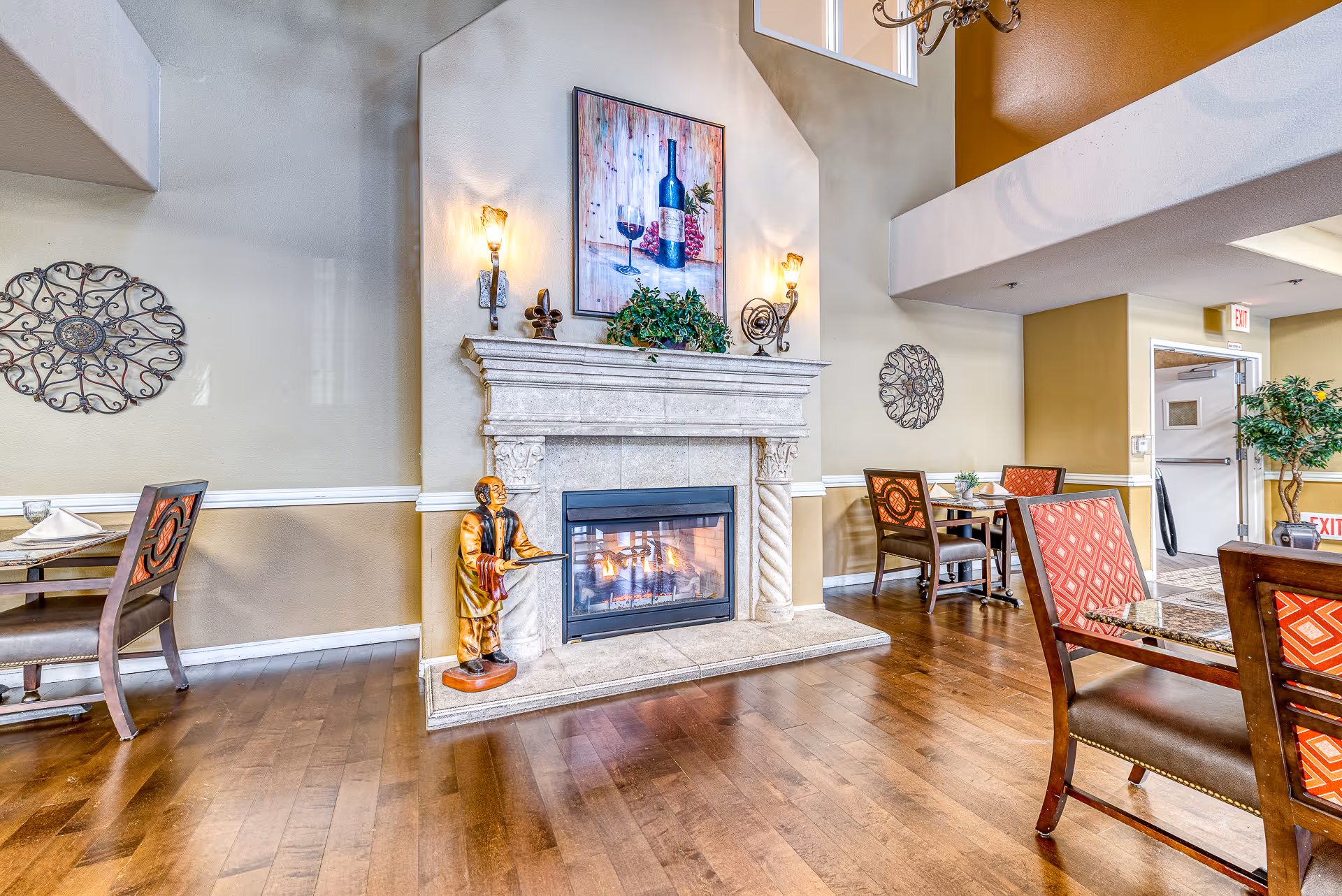Bright common dining area with a decorative fireplace, tables and chairs on hardwood floors.