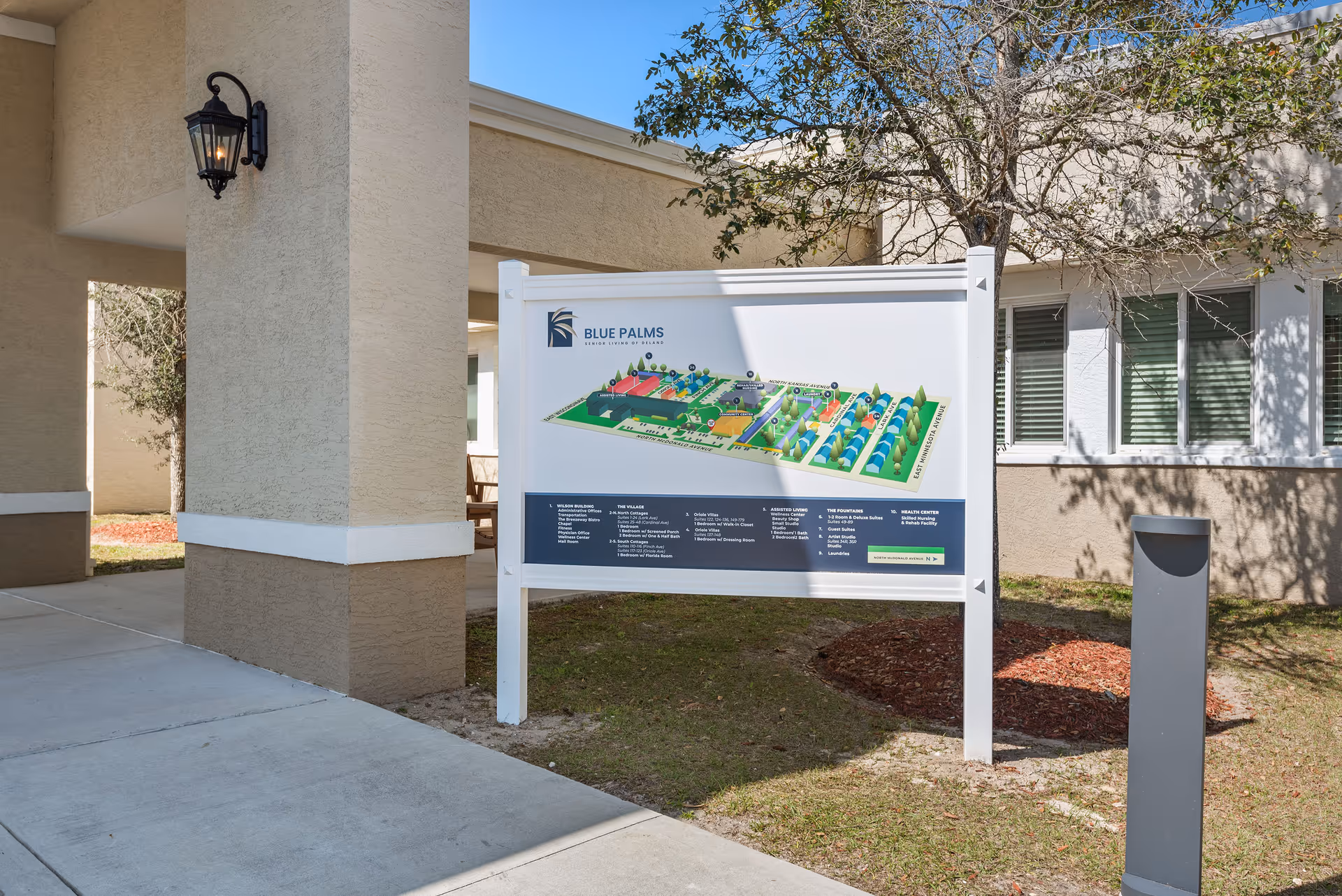 Outdoor entrance area showing a freestanding Blue Palms campus map sign in front of the building.