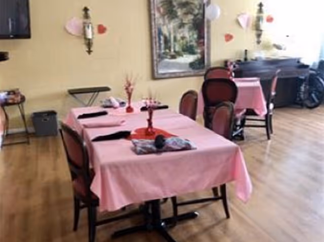 Dining room with tables covered in pink tablecloths, chairs, and wall decorations.