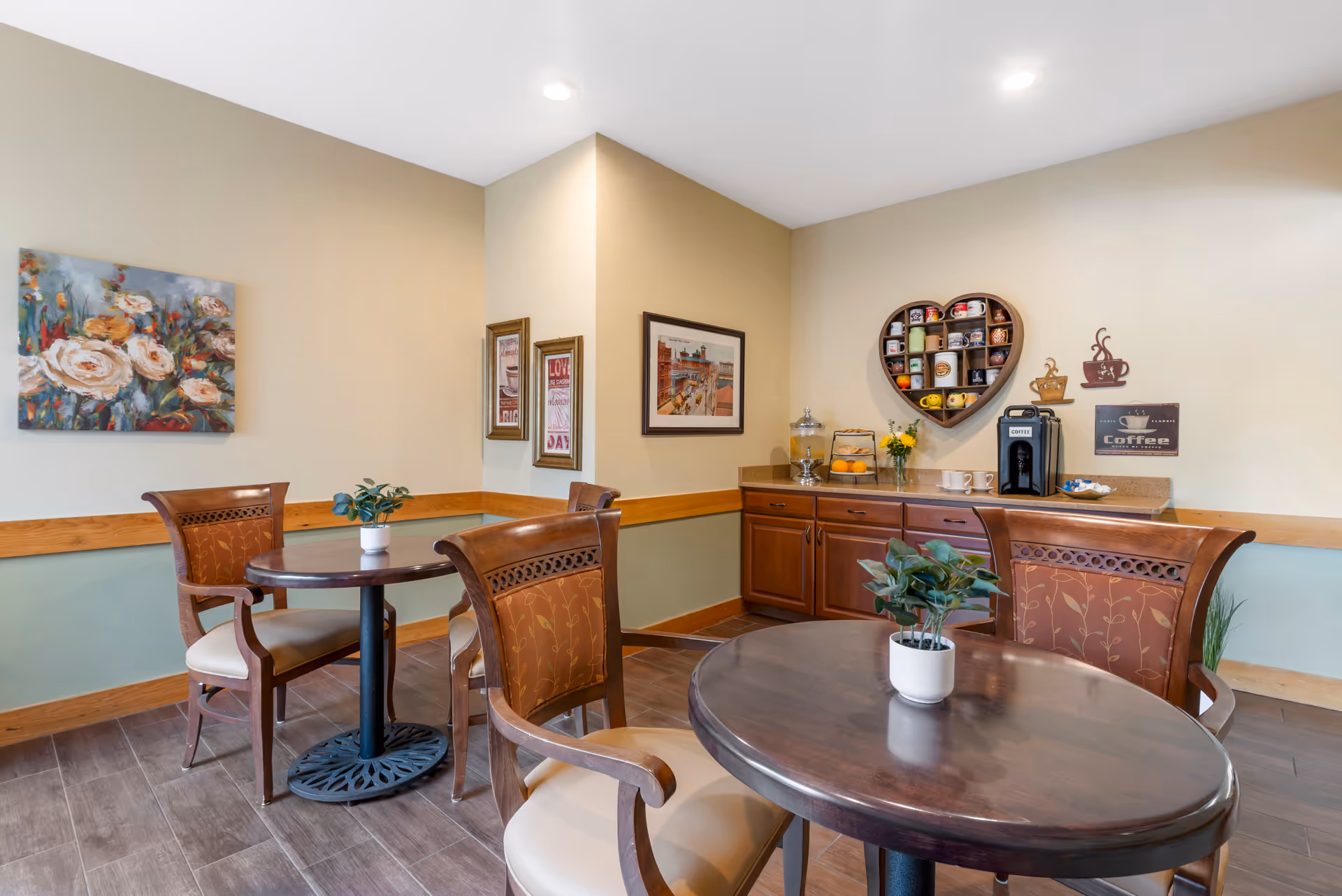 Small dining/lounge area with round tables and chairs and a countertop coffee station with wall decor.