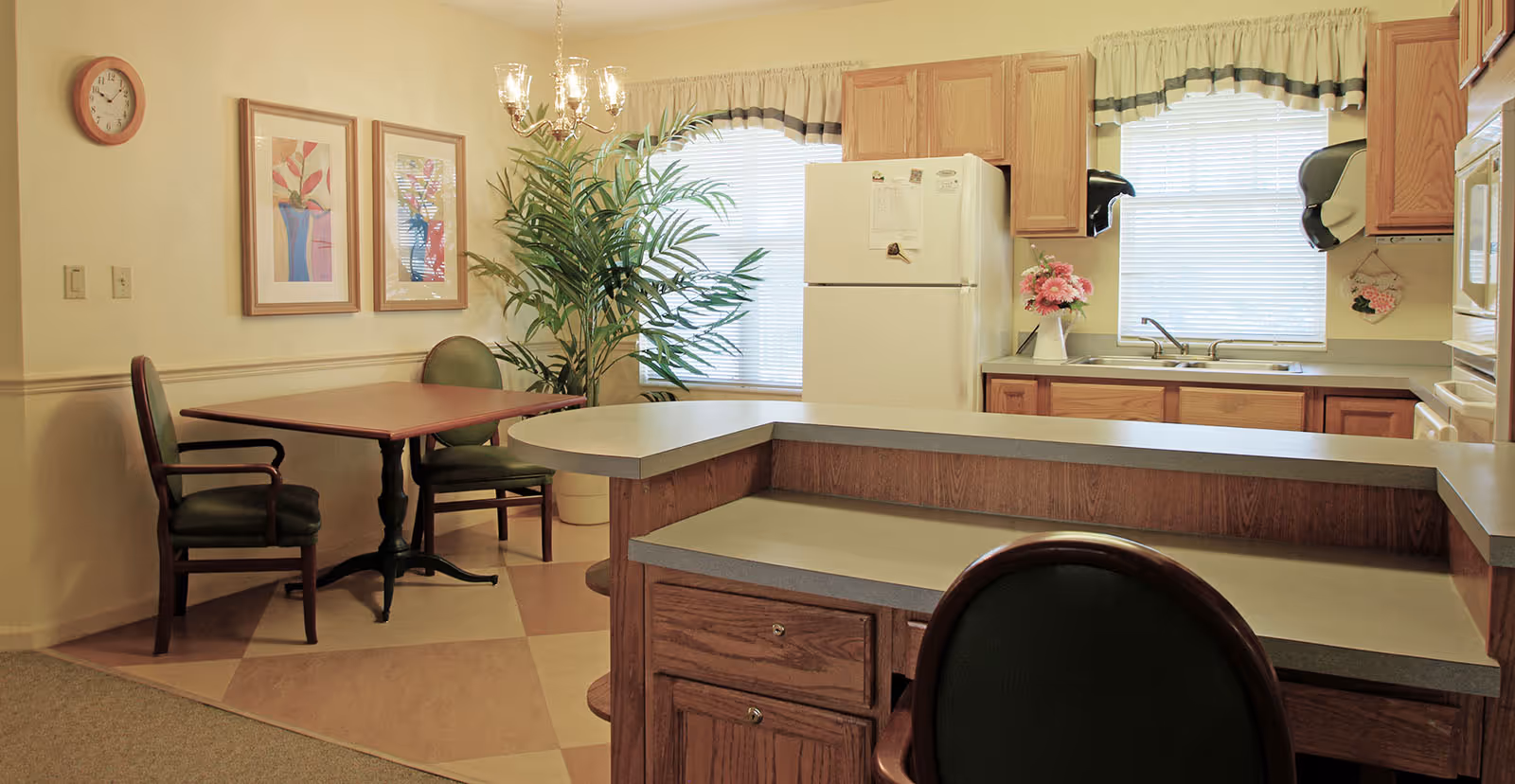 Cozy kitchen and dining nook with a countertop island, refrigerator, sink, and a small table with chairs.