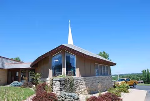 Exterior view of a senior living facility with stone veneer base and a white steeple.