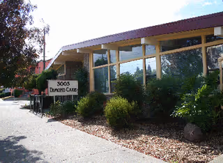 Exterior view of a single-story Dimond Care LLC facility with windows and shrubs.