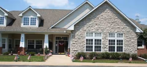 Exterior of The Addison of Cornersburg, a stone-faced senior living facility with a covered entrance.