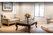 Bright living room with beige furniture, a wooden coffee table, and flowers.