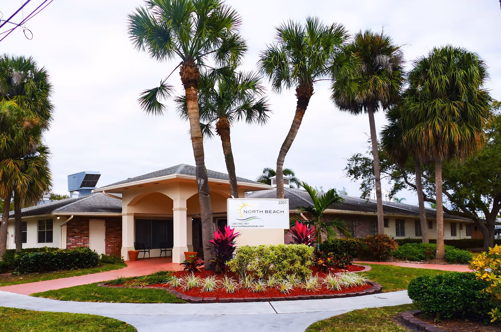 Entrance of North Beach Rehabilitation Center, a single-story building with palm trees and landscaped grounds.