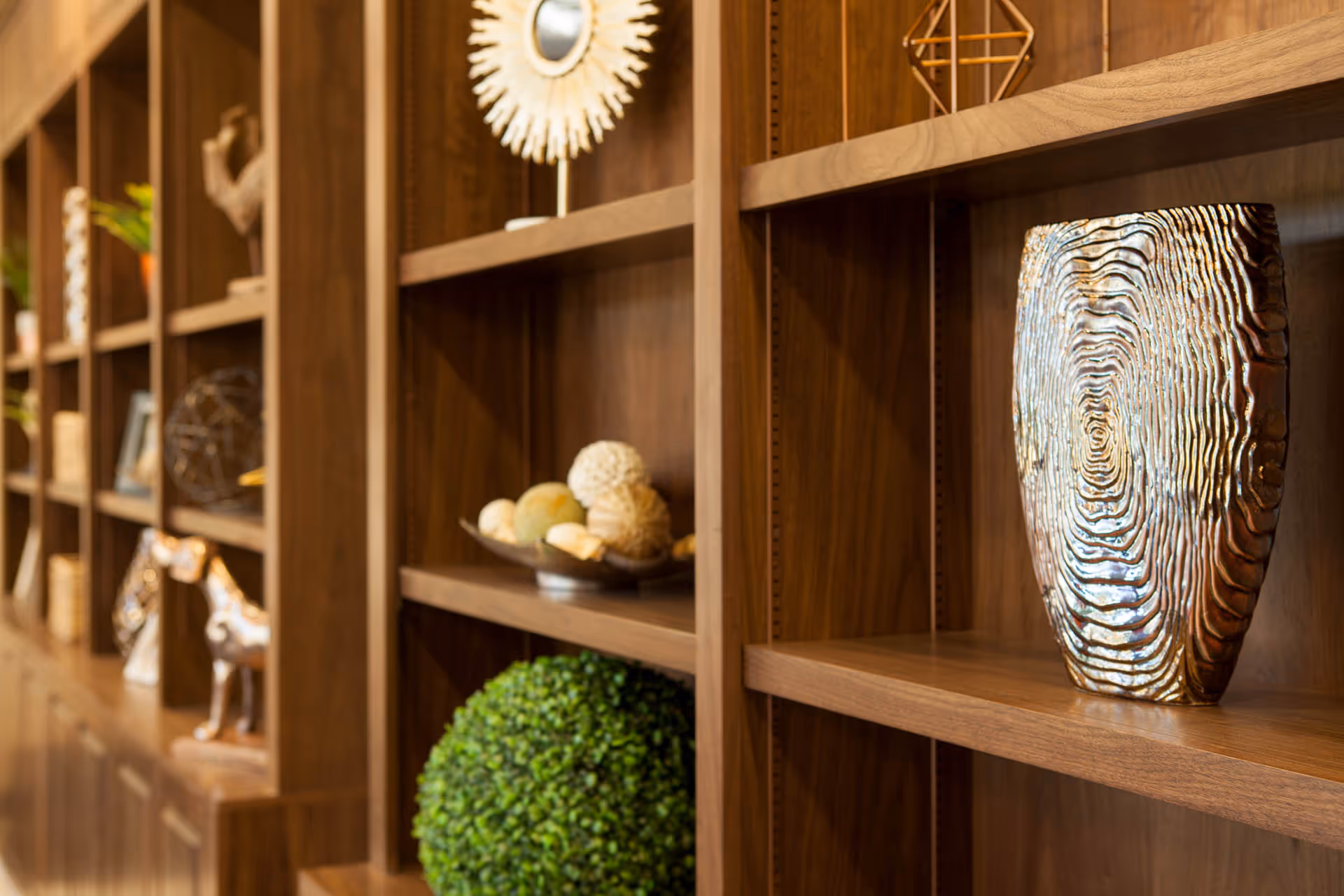 Built-in wooden shelves filled with decorative vases, sculptures, and greenery.