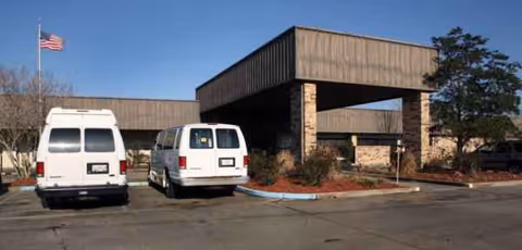 Front view of Patterson Healthcare Center entrance with two white vans in parking lot.
