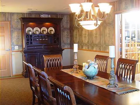 A dining room with a long wooden table, chandelier, and china cabinet.
