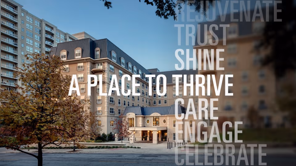 Exterior view of a multi-story senior living facility building with a driveway and trees in front, under a clear blue sky. Overlaid text reads: 'A PLACE TO THRIVE' along with words like REJUVENATE, TRUST, SHINE, CARE, ENGAGE, and CELEBRATE.