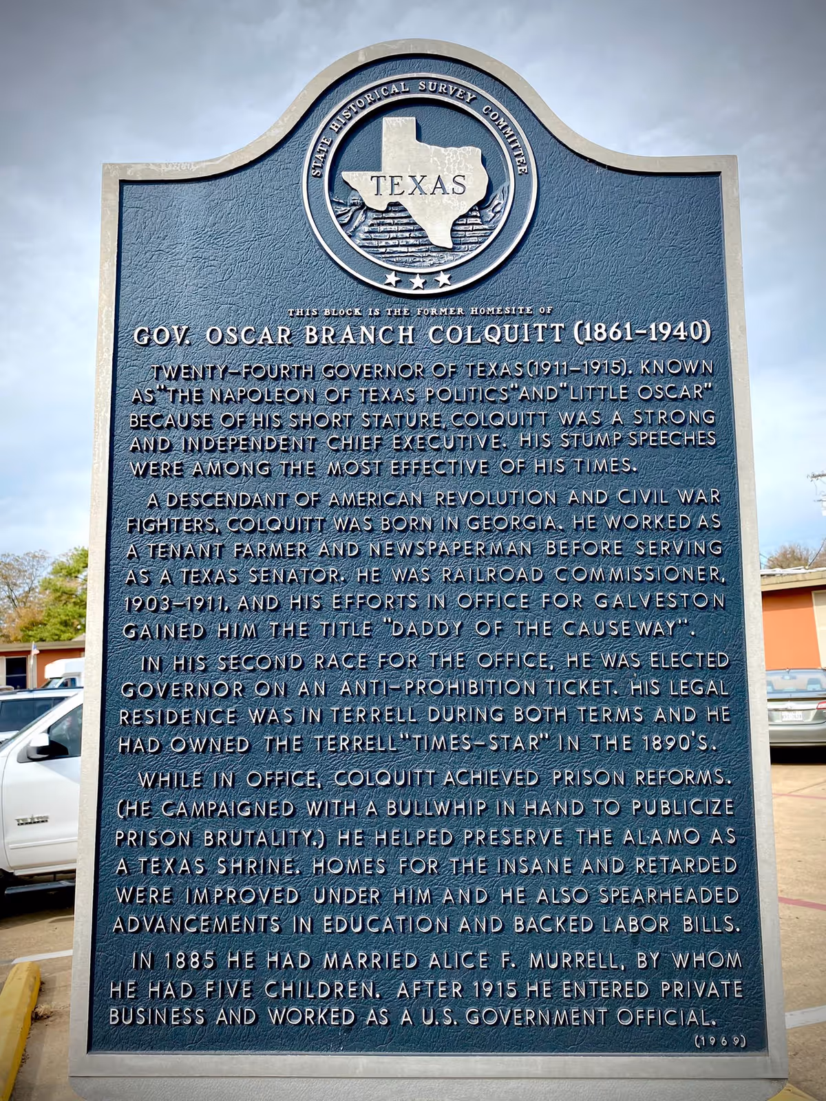 Historic Texas plaque about Gov. Oscar Branch Colquitt with a Texas seal, displayed outdoors in a parking area.