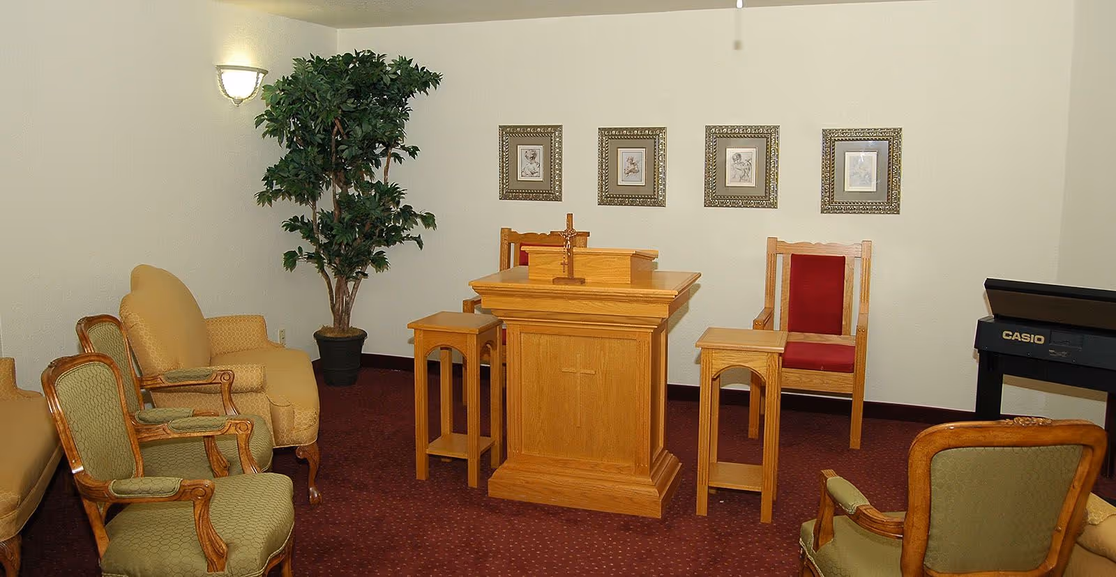 Small chapel-style interior featuring a wooden pulpit and several upholstered chairs arranged around it.