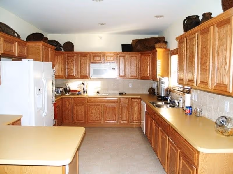 Bright kitchen with oak cabinets, beige countertops, a white refrigerator and microwave, and a small island.