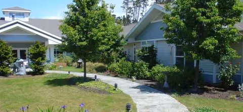 Exterior view of Golden Sands senior living facility with curved walkway and green trees.