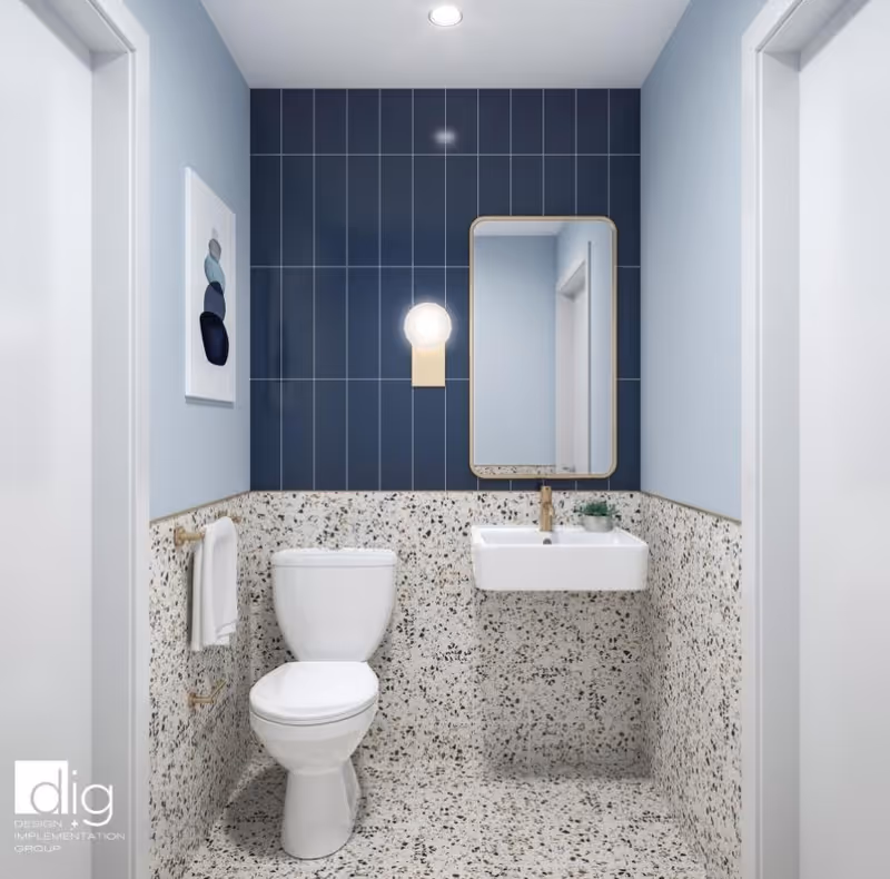 A modern bathroom with terrazzo flooring and lower wall tiles, a white toilet, a wall-mounted white sink with a gold faucet, a rectangular mirror with a gold frame, a round wall light above the sink, and a towel hanging on a gold towel rack. The upper wall behind the sink and toilet is covered with vertical dark blue tiles, and there is a framed abstract artwork on the left wall.