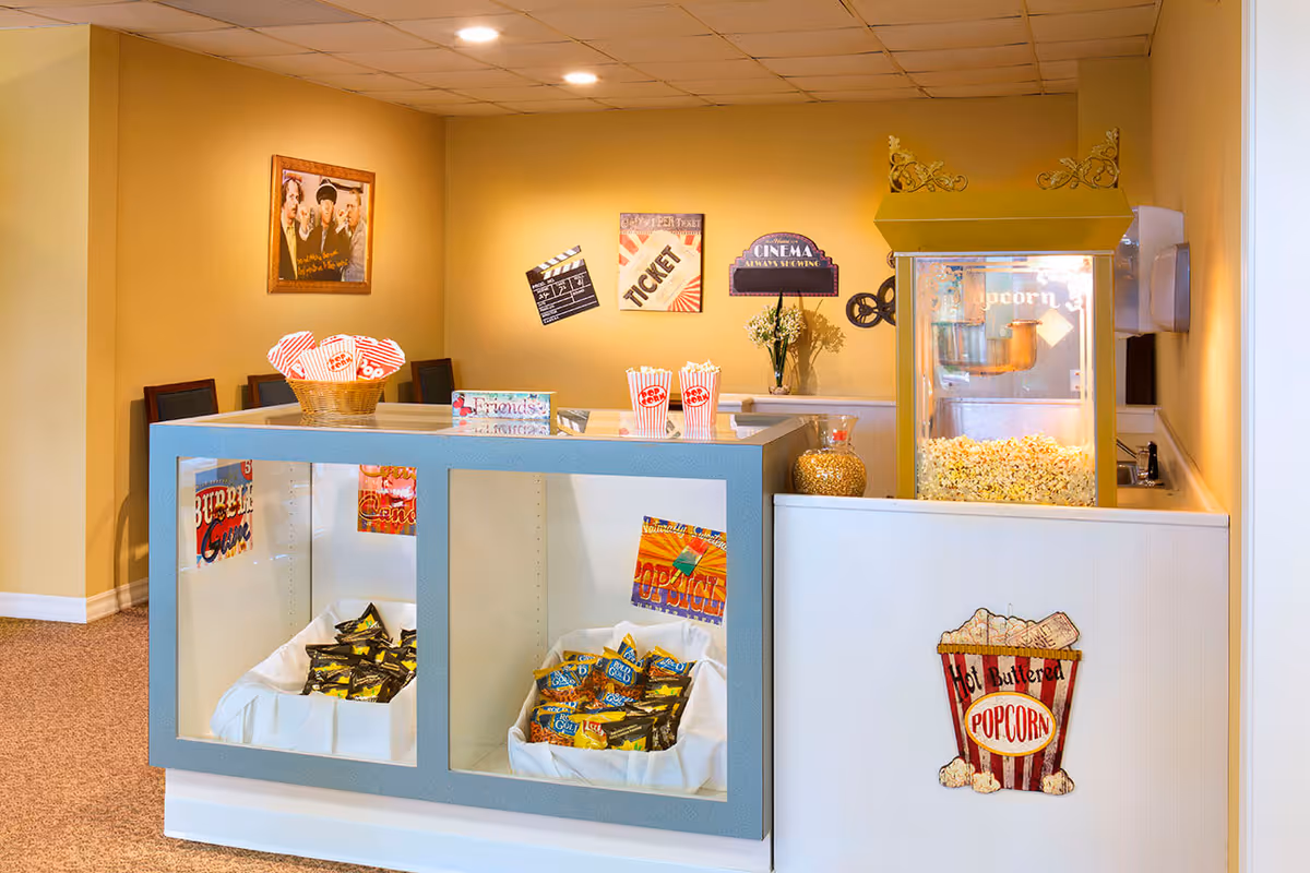 Concession-style snack counter with a popcorn machine, bins of candy, popcorn tubs, and movie-themed decor.