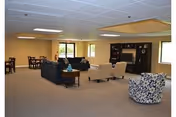 Spacious senior living lounge with sofas, chairs, coffee tables, and a fireplace.