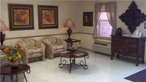 Hartville Care Center living room: bright lounge with floral sofas, lamps, and a round coffee table.