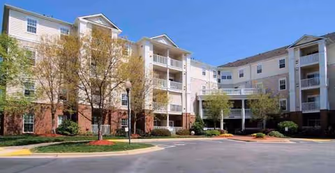 Exterior view of Gardens at Wakefield building with balconies, parking lot, and trees.