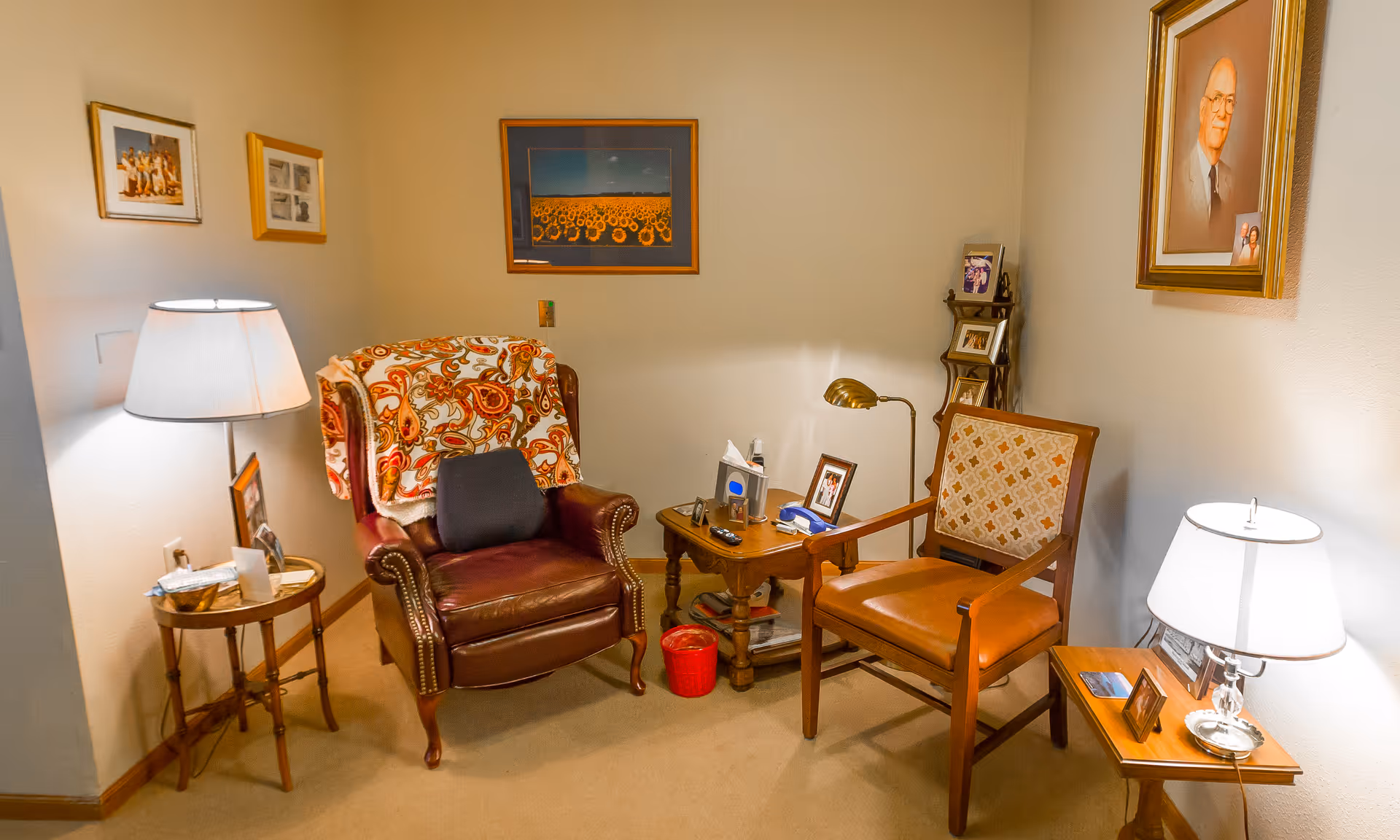 Cozy sitting area with two armchairs, side tables, lamps, framed pictures and a small coffee table.