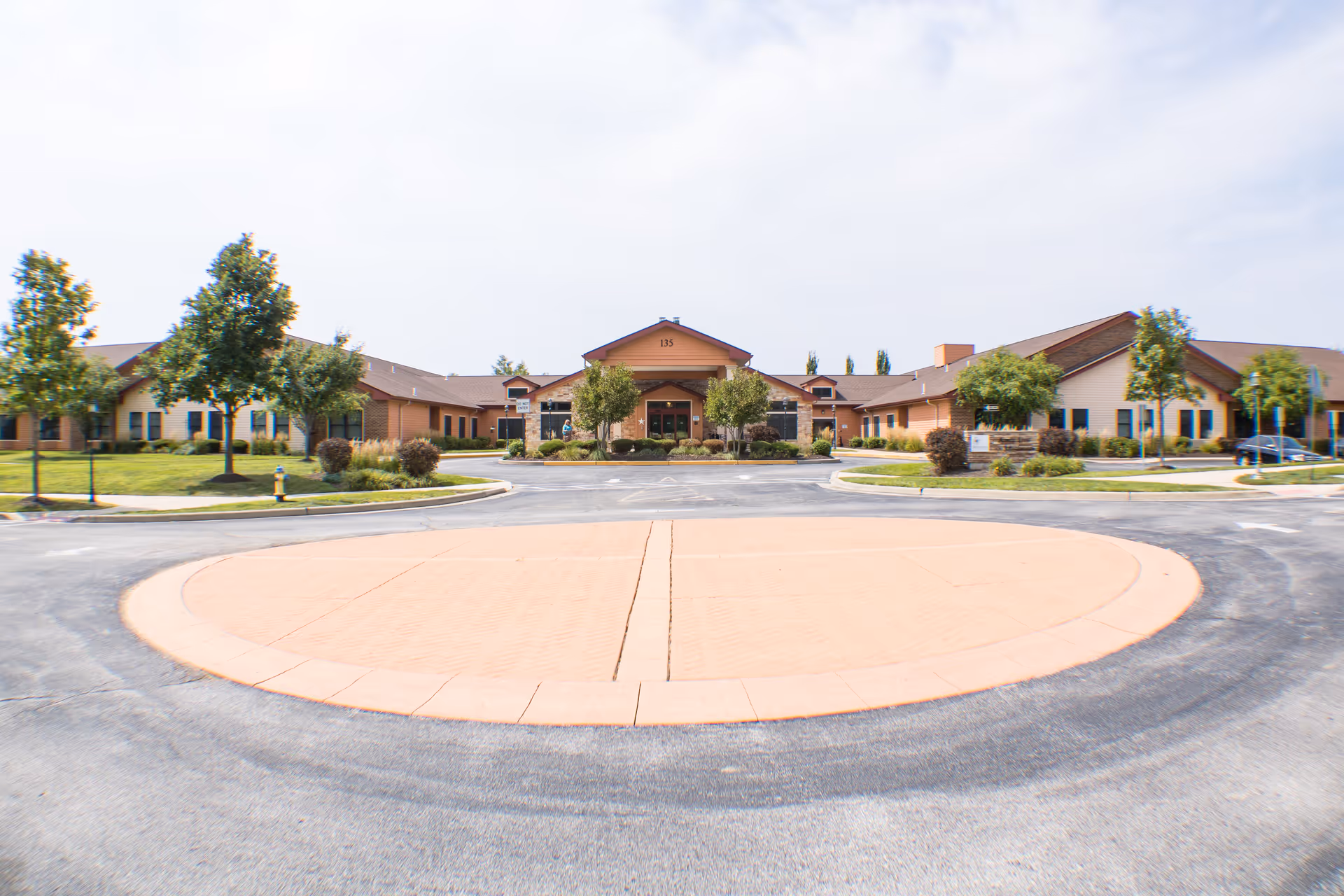 Front exterior of The Meadowlands senior living facility showing a single-story building with a circular driveway and landscaped lawns.