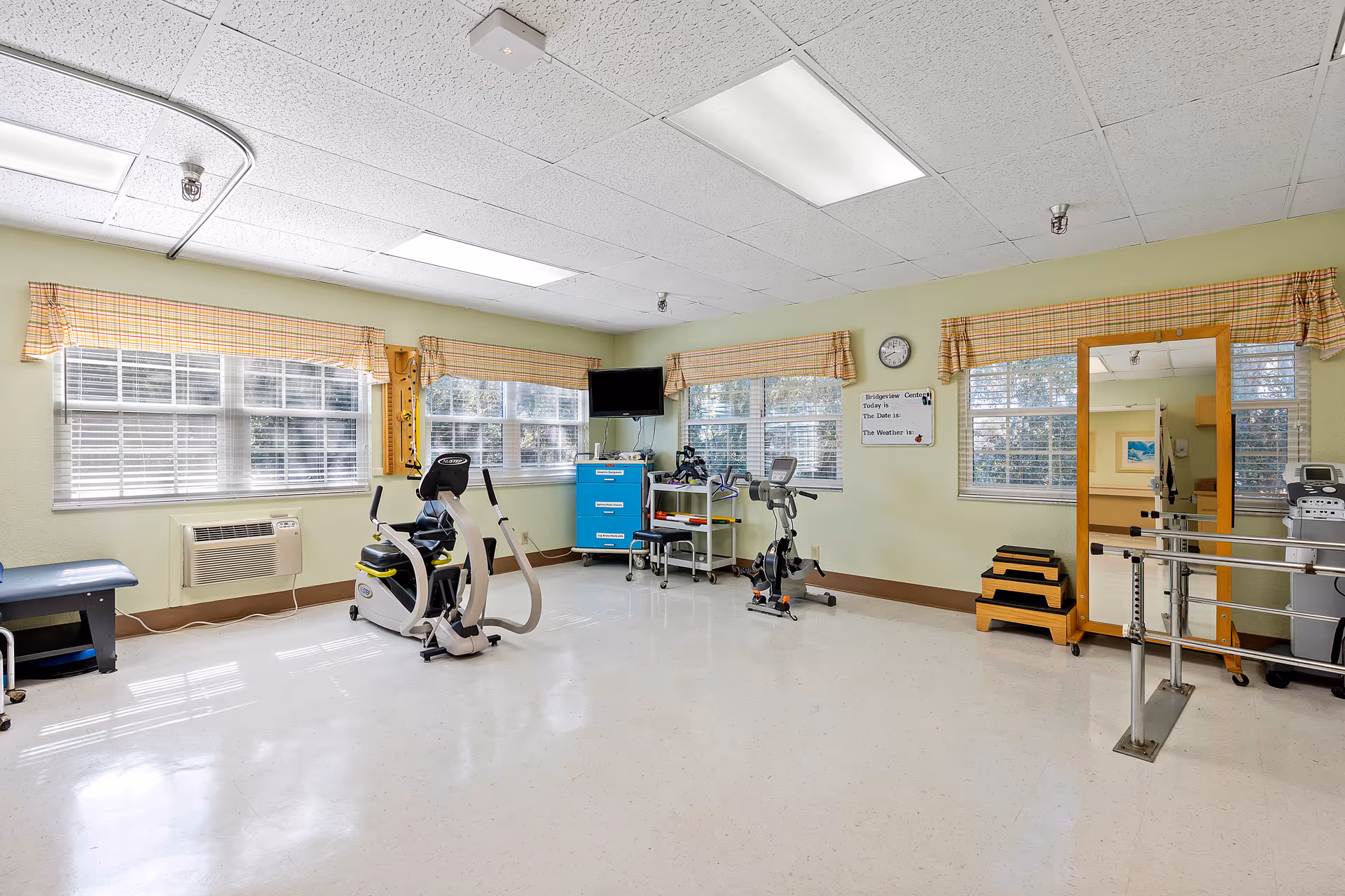 A bright and spacious exercise area with fitness equipment and large windows.