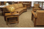 Community living room with a sofa, upholstered chairs, wooden end tables, a globe and bookshelves near window blinds.
