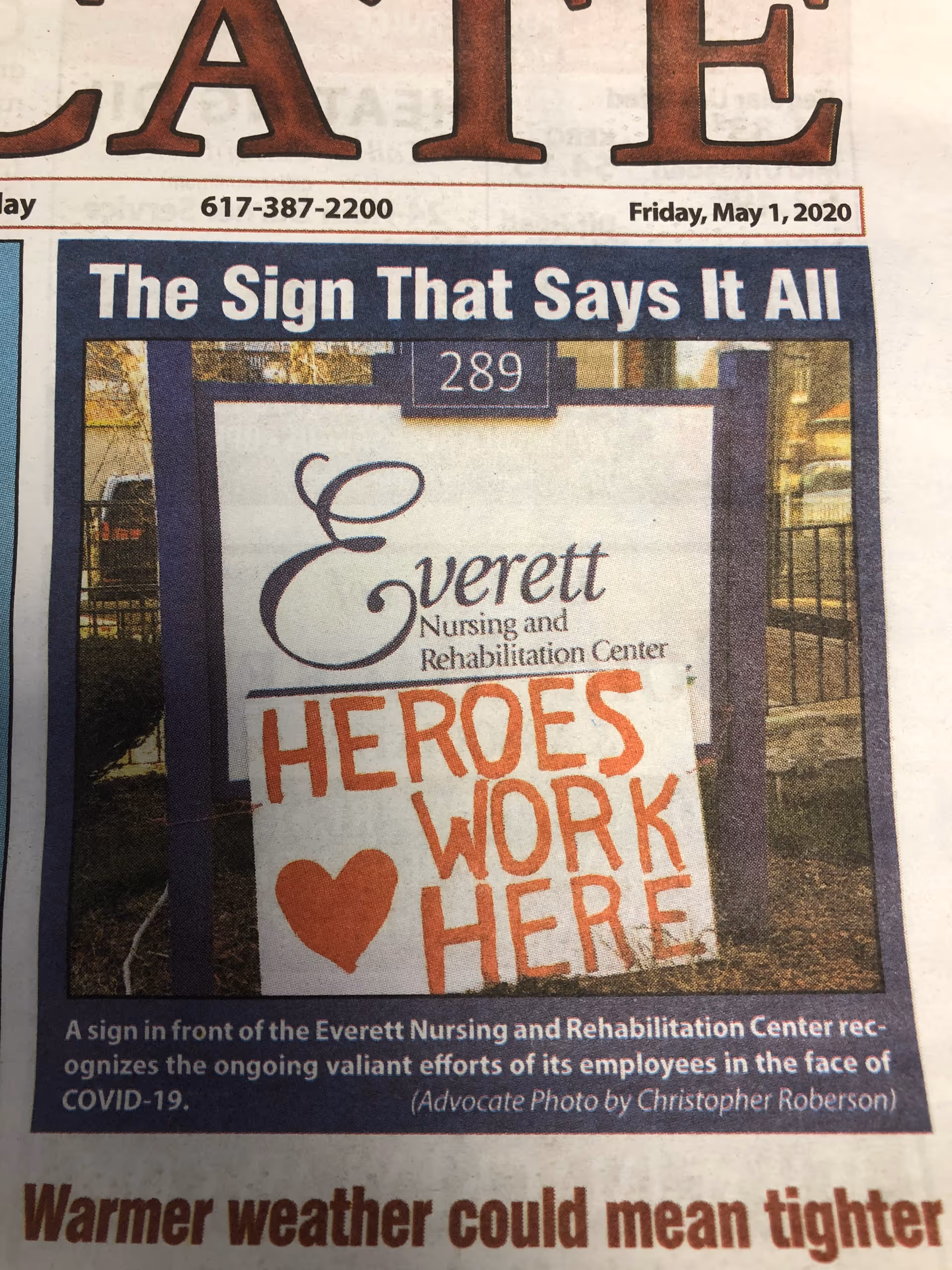 Newspaper photo of the Everett Nursing and Rehabilitation Center sign with a handwritten 'HEROES WORK HERE' poster and a heart.