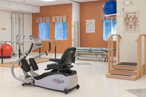 Indoor rehab gym in a senior facility with exercise equipment and therapy stairs.