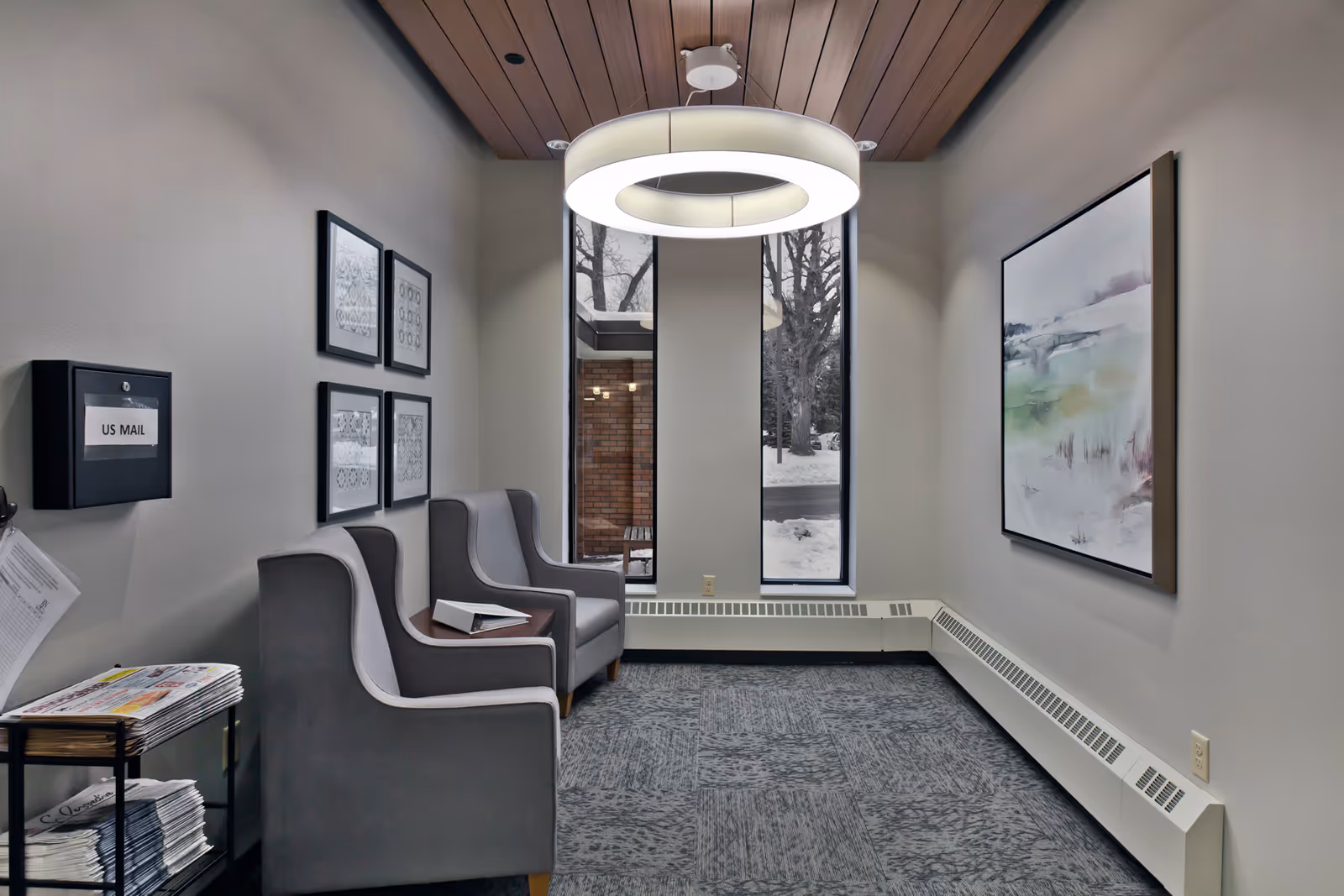 Small interior seating area with two gray armchairs, a circular ceiling light, wall art, and a US Mail box.