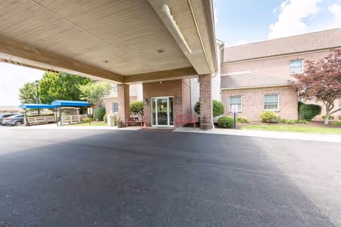 Covered drop-off area in front of the brick senior living facility entrance.