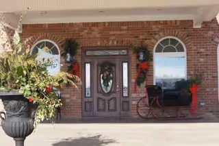 Brick building entrance with arched windows, double doors, and decorative red garlands.