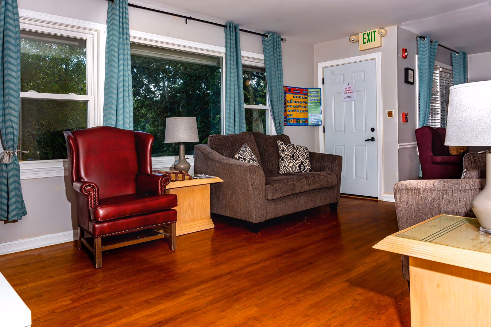 A cozy seating area in a senior living facility with a red armchair and a brown sofa.
