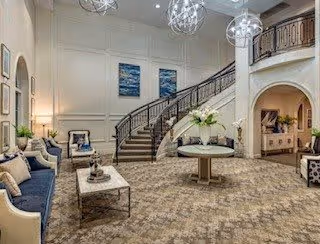 Spacious elegant lobby with a curved staircase, seating area, and decorative pendant lights.