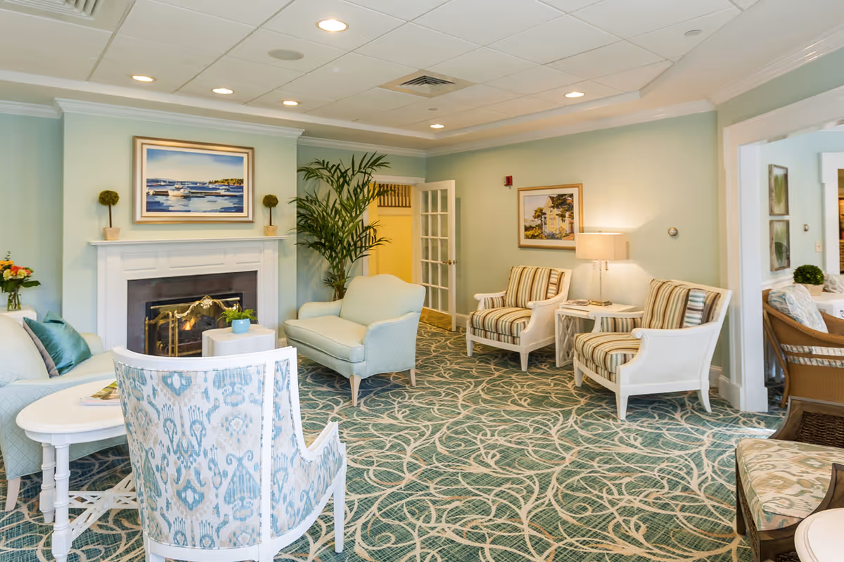 Bright pastel-toned sitting room with upholstered chairs, a fireplace, and patterned carpet.