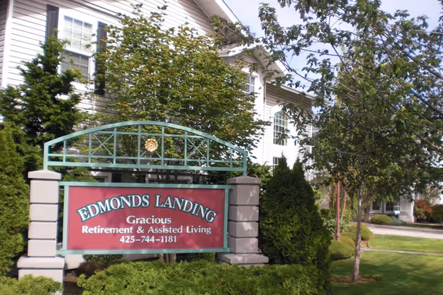 A landscaped entrance sign for "Edmonds Landing" retirement and assisted living in front of a multi-story building.