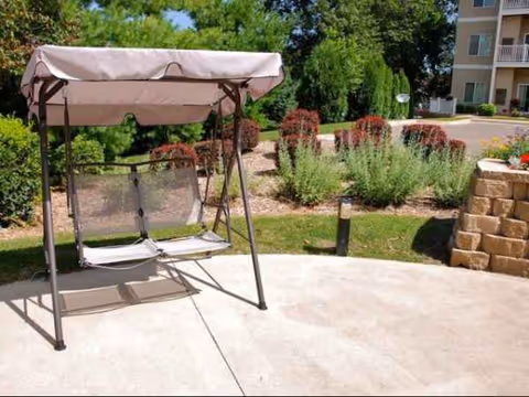 Outdoor patio with a pink-canopy swing and landscaped garden beds.
