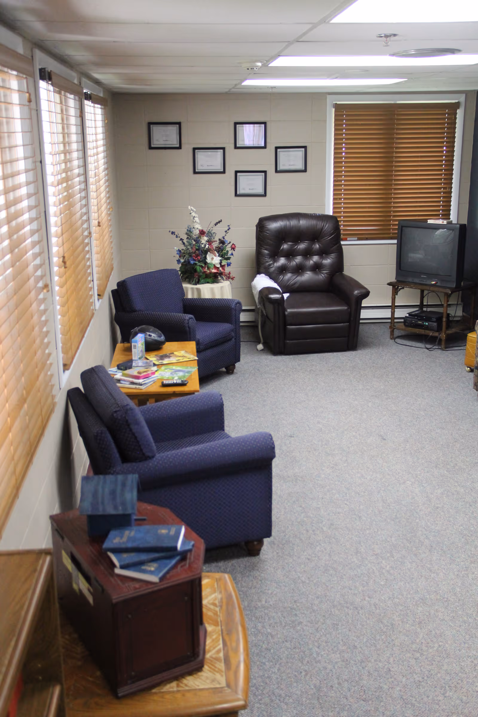 Small sitting room with upholstered armchairs, a leather recliner, side tables, and a TV.