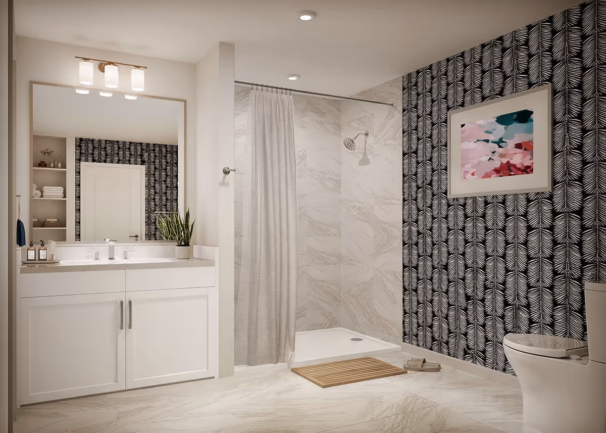 Modern bathroom with a white vanity featuring a large mirror and three-light fixture above it. There is a walk-in shower with a gray curtain and marble-patterned tiles. The wall behind the toilet has black and white leaf-patterned wallpaper and a colorful abstract painting. A wooden bath mat and slippers are placed on the floor.